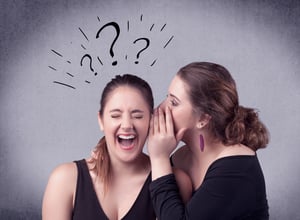 A teenager girl looking confused with drawn question marks above the head, while a girlfriend whispers something in her ear concept.
